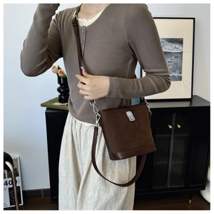 Detail of vintage brown suede bucket bag with silver metal buckle and leather strap