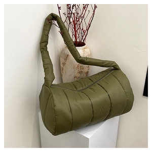 Detail of olive green quilted down shoulder bag with padded strap on a white pedestal
