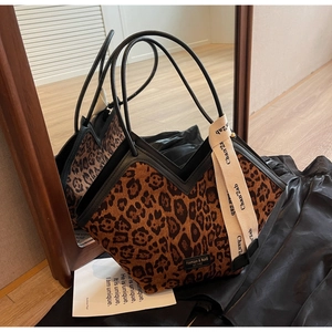 Dettaglio riflesso della borsa tote leopardata con manici neri e nastro decorativo chic