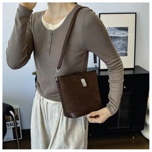 Detail of dark brown retro bucket bag with silver buckle and suede texture on model