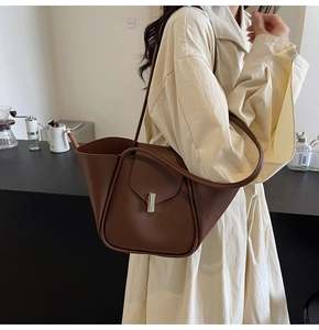 Détail d'un sac cabas en cuir marron avec fermoir tournant cylindrique doré et bord plié