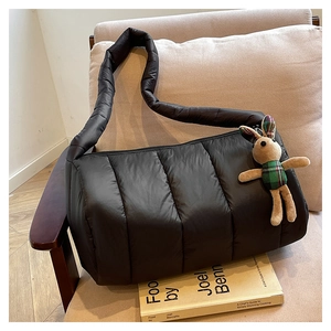 Close-up of black quilted down shoulder bag on a chair with a plush rabbit charm