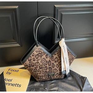 Dettaglio della borsa tote leopardata con finiture in pelle nera e nastro decorativo