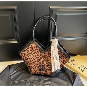 Dettaglio della borsa leopardata con manici in pelle nera e foulard decorativo chic
