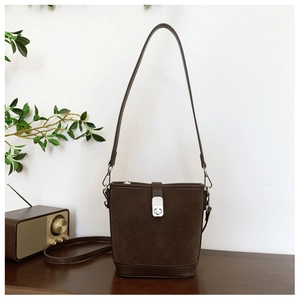 Detail of dark brown vintage suede bucket bag with silver metal buckle and leather trim