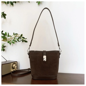 Detail of dark brown suede bucket bag with silver metal buckle and adjustable strap