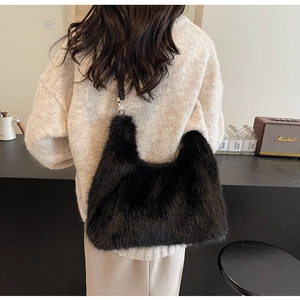 Schicke schwarze Kunstpelz-Handtasche mit Lederriemen in trendiger Café-Atmosphäre