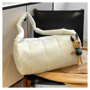 Close-up of white quilted cylinder pillow bag featuring a cute brown rabbit plush charm