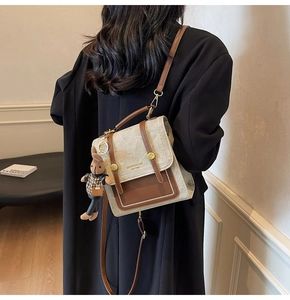 Detail of vintage crossbody bag with brown leather trim and a cute plush rabbit pendant