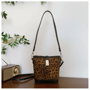 Detail view of leopard print bucket bag featuring silver buckle on a rustic wooden table
