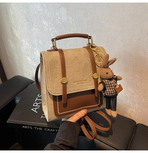 Close-up of retro khaki canvas backpack with leather straps and a rabbit charm