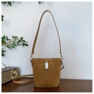 Close-up of brown suede bucket bag with silver metal twist lock and leather stitching