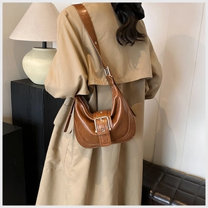 Nahaufnahme der braunen Retro-Hobo-Tasche kombiniert mit einem khakifarbenen Trenchcoat