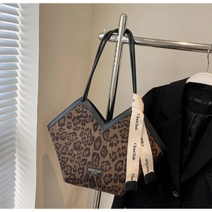 Dettaglio della borsa tote con stampa leopardata, nastro decorativo ed etichetta logo