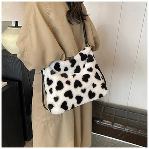 Détail d'un sac à bandoulière en peluche à motif cœurs porté par un mannequin