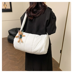 Detailed view of white quilted puffer barrel bag with a cute plush animal pendant
