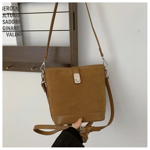 Detail of vintage brown bucket bag showing suede texture and metal push-lock clasp