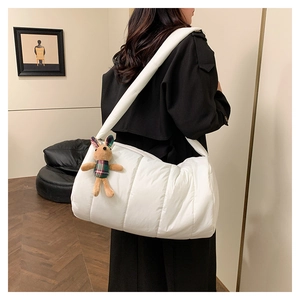 Detail of white quilted puffy handbag with a cute brown plush rabbit pendant accessory
