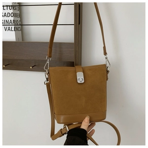 Close-up of brown suede bucket bag with metallic buckle and vintage minimalist design