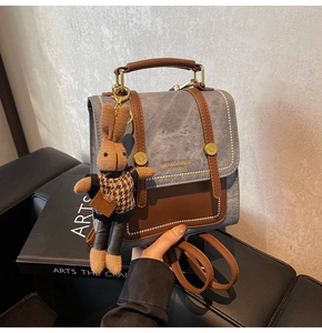Detail of vintage square backpack with denim texture, leather trim and rabbit charm