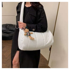 Detail of white quilted down shoulder bag with brown rabbit plush charm on a model