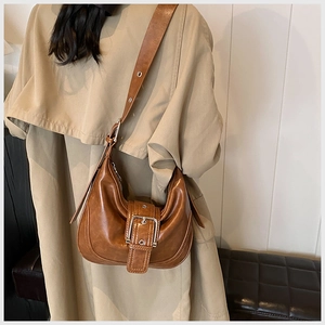 Braune Retro-Hobo-Tasche mit Metallschnalle getragen auf einem stylischen Trenchcoat