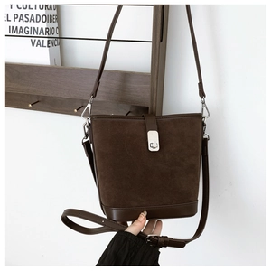 Detail of vintage brown suede bucket bag with leather trim and silver metal buckle