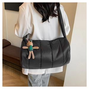 Detail of black quilted puffer cylinder bag featuring a cute green plaid bunny charm