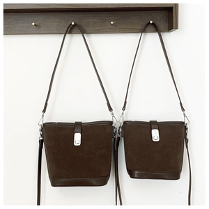 Detail view of two dark brown suede bucket bags in different sizes with silver buckles