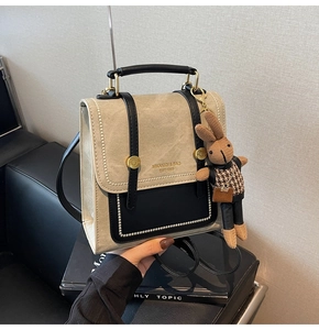 Detail of vintage beige and black backpack with plush bunny charm and golden logo