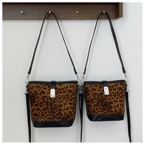 Detail view of two leopard print bucket bags with black trim and silver hardware hooks