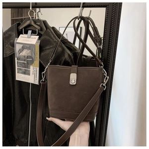 Detail of vintage dark brown suede bucket bag featuring silver turn-lock metal closure