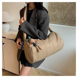 Quilted beige puffer crossbody bag with a cute rabbit plush charm shown in a cozy setting