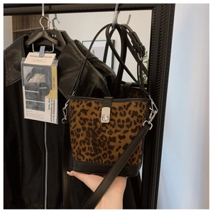 Detail of leopard print bucket bag with metal twist lock and leather trim strap