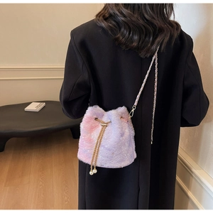 Detail view of purple plush bucket bag with golden chain and pearl drawstring charms