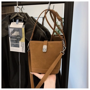 Detail of caramel brown suede bucket bag with silver metal clasp and slim shoulder strap