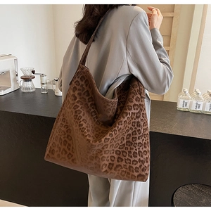 Detailed view of leopard print suede tote bag carried by model in cafe setting
