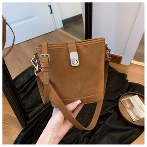 Detail of vintage brown suede bucket bag featuring silver twist-lock and smooth leather trim
