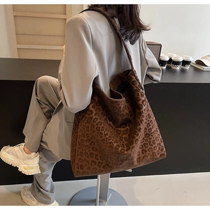 Detail of a large leopard print tote bag with a soft texture and matching wide shoulder strap