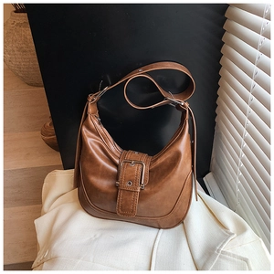 Detail der karamellbraunen Hobo-Tasche mit großer Schnalle auf hellem Blazer