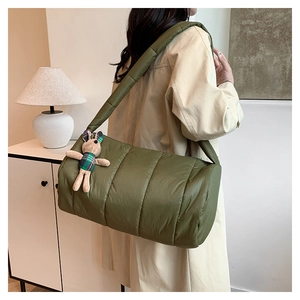 Detail of green quilted down crossbody bag with cute rabbit pendant and wide strap