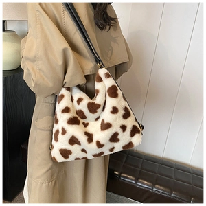 Gros plan d'un sac en peluche à motifs cœurs bruns avec bandoulière sur un mannequin