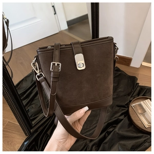Detail of dark brown suede handbag with leather trim and silver metal push-lock