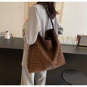Brown leopard print tote bag shown on shoulder in a warm lifestyle cafe setting