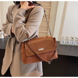 Nahaufnahme der braunen Ledertasche mit silbernem YOUBER Logo und Kettenriemen