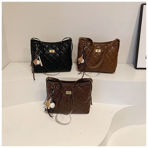 Détail de sacs matelassés en noir et marron avec fermoir métallique et breloque de baseball