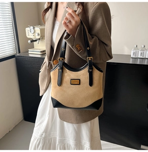 Detail einer braunen Wildleder- und schwarzen Leder-Patchwork-Tasche mit Goldlogo