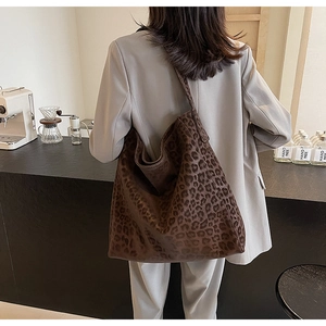 Close-up of leopard print tote bag on a model in a cafe, showing soft suede texture