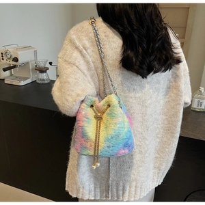 Close-up of plush rainbow bucket bag with gold chain strap and pearl accents on a model