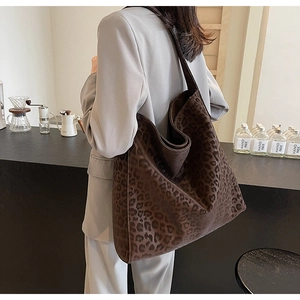 Brown leopard print suede tote bag styled with a grey suit in a minimalist cafe